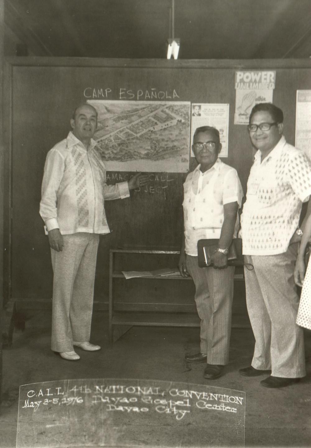 Stanley and two men in front of a black board and a diagram labeled "Camp Española"