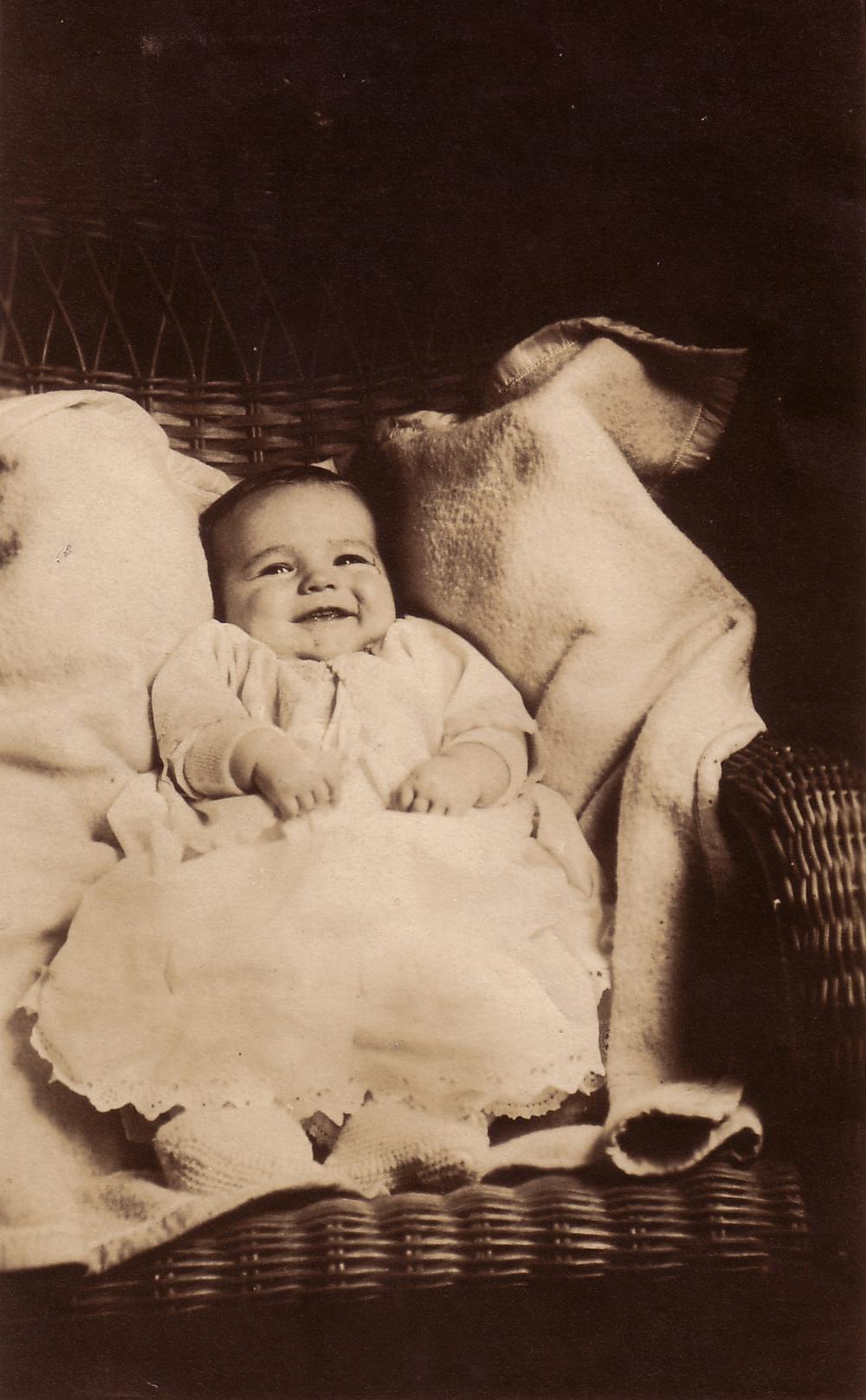 Stanley as a baby, laying in a wicker chair with blankets