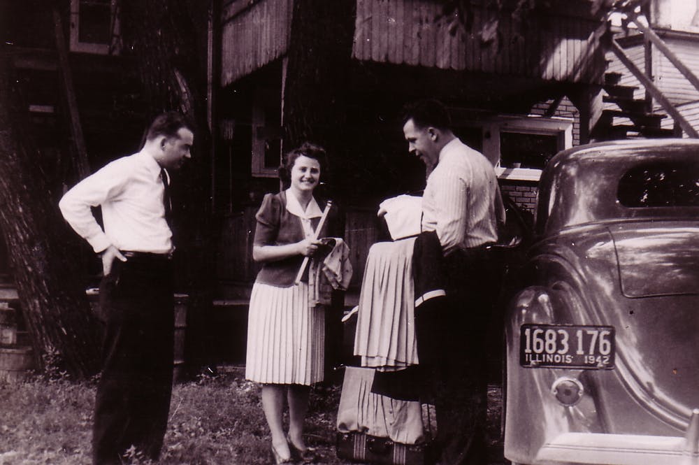 Stanley, Bob & Harriet in front of a building and talking around a car