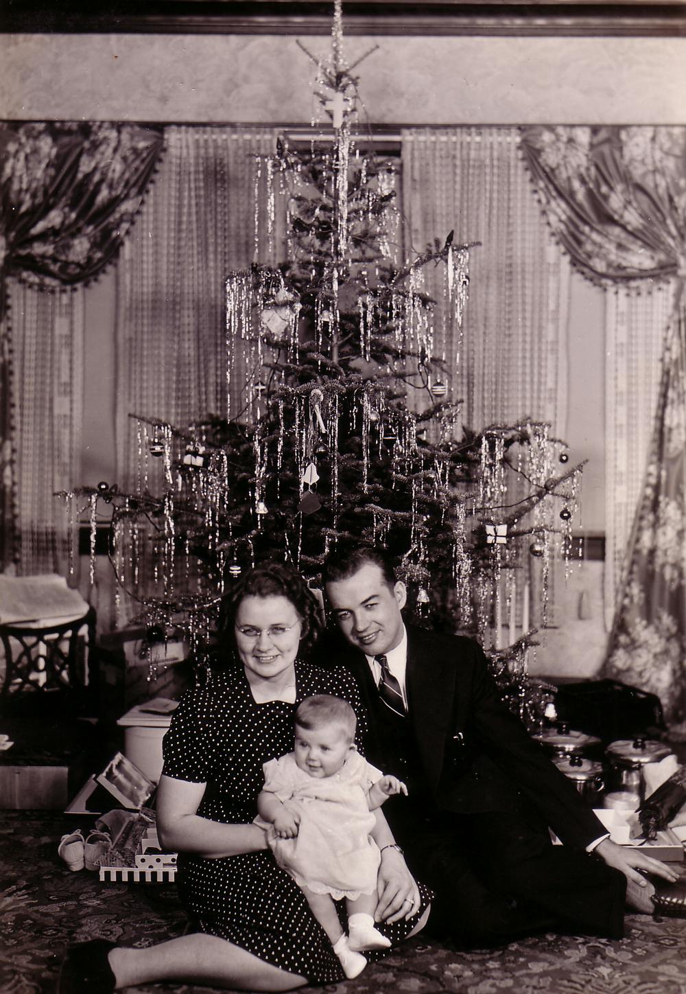 Stanley with his wife and young daughter seated in front of a Christmas tree
